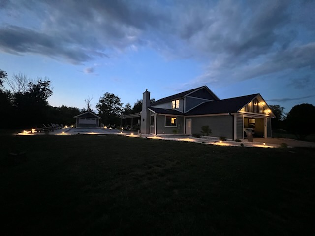 Exterior shot of house at night with well-lit driveway and walkways